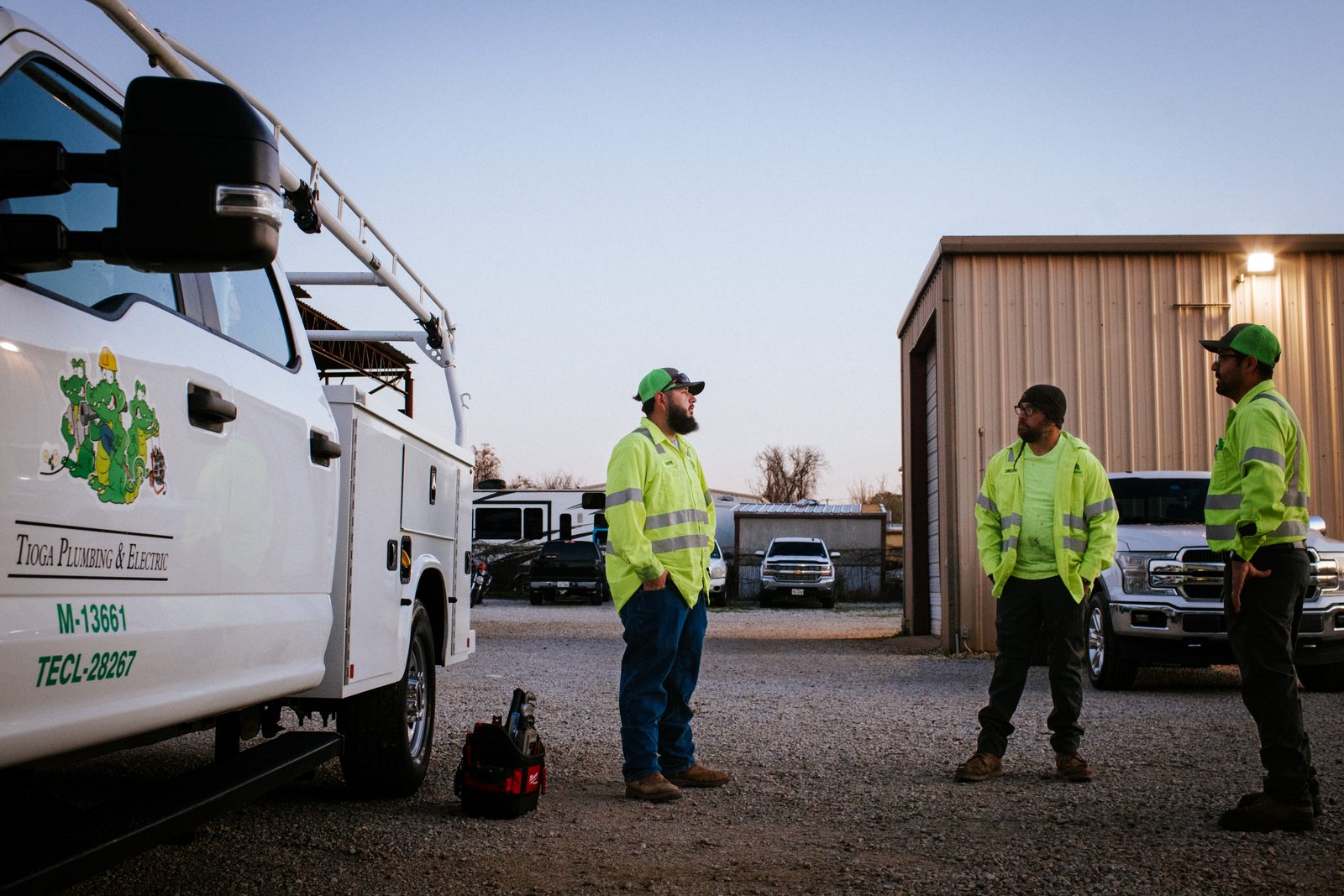 Tioga Plumbing technicians talking beside a branded service truck in the Hurst, TX yard at dusk